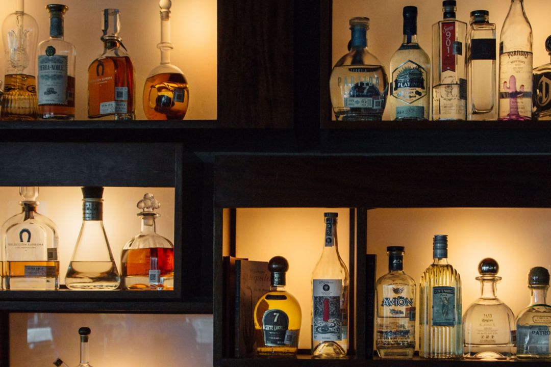 Muro de tequila y mezcal de Agave Azul retroiluminado